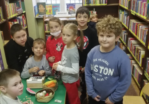 Dzieci w bibliotece przy regałach z książkami.